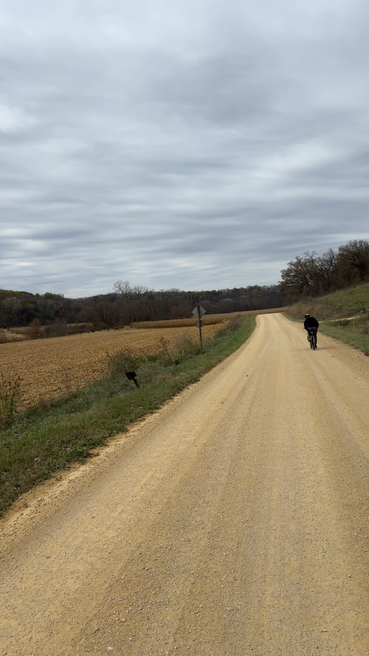 Gravel road rider ahead under cloudy sky